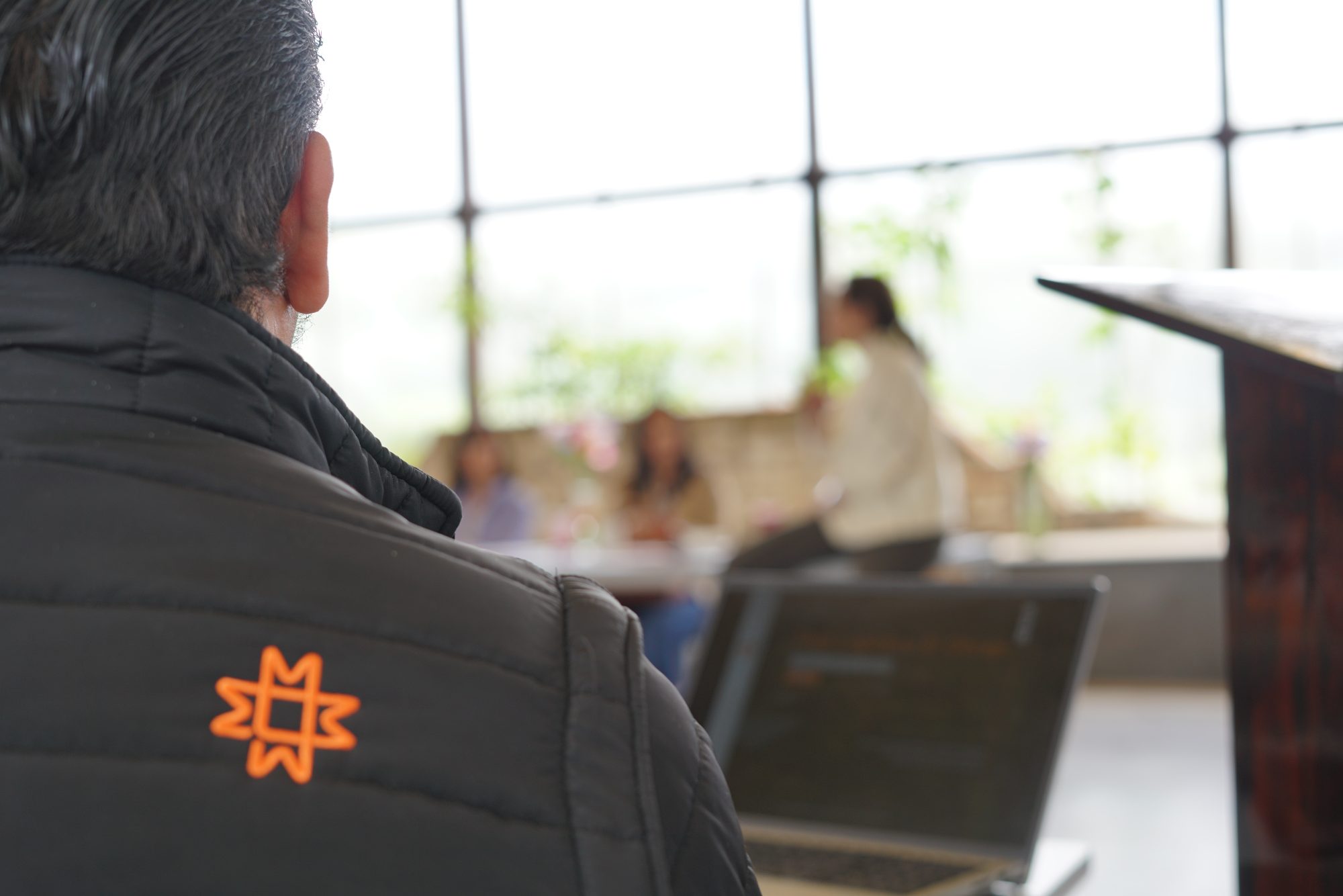 Integrante del equipo de AdminObraje con chaqueta del parque en una reunión